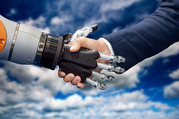 Image showing Hand of a businessman shaking hands with a Android robot.