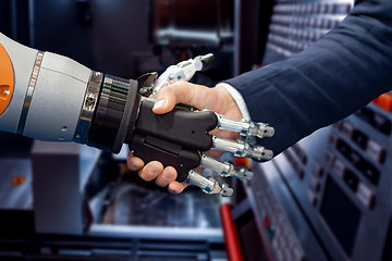 Image showing Hand of a businessman shaking hands with a Android robot.