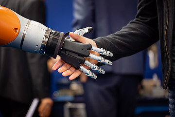 Image showing Hand of a businessman shaking hands with a Android robot.