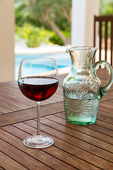 Image showing Glass of red wine in poolside