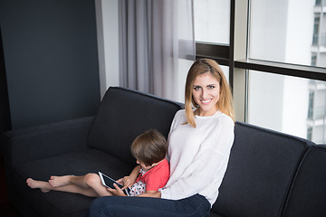 Image showing mother and her cute little daughter are using a tablet