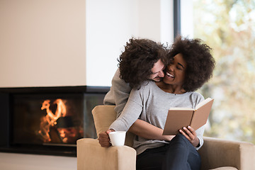 Image showing multiethnic couple hugging in front of fireplace