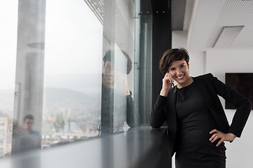 Image showing Elegant Woman Using Mobile Phone by window in office building