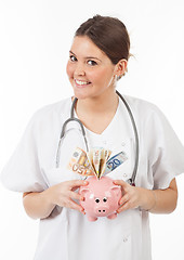 Image showing happy woman doctor with piggy bank full of money