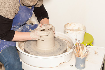 Image showing Female Potter creating a earthen jar on a Potter\'s wheel