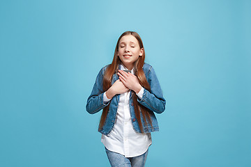 Image showing The happy teen girl standing and smiling against blue background.