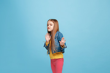 Image showing Doubtful pensive teen girl rejecting something against blue background