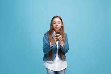 Image showing The happy teen girl standing and smiling against blue background.