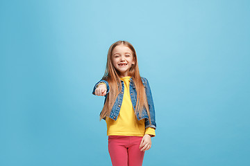 Image showing The happy teen girl pointing to you, half length closeup portrait on blue background.