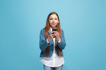 Image showing The happy teen girl standing and smiling against blue background.