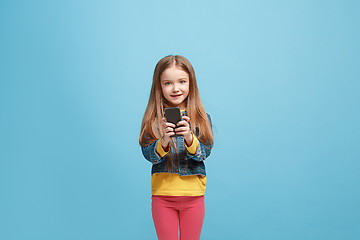 Image showing The happy teen girl standing and smiling against blue background.