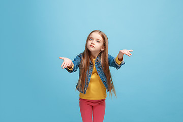 Image showing Beautiful female half-length portrait on blue studio backgroud. The young emotional teen girl