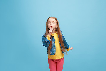 Image showing The young teen girl whispering a secret behind her hand over blue background