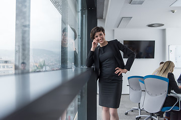 Image showing Elegant Woman Using Mobile Phone by window in office building