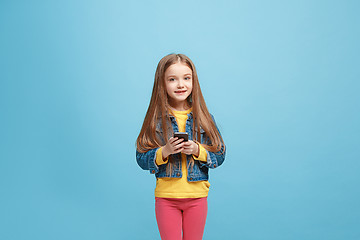 Image showing The happy teen girl standing and smiling against blue background.