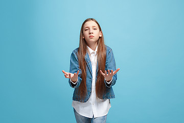 Image showing Beautiful female half-length portrait on blue studio backgroud. The young emotional teen girl