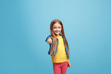 Image showing The happy teen girl pointing to you, half length closeup portrait on blue background.