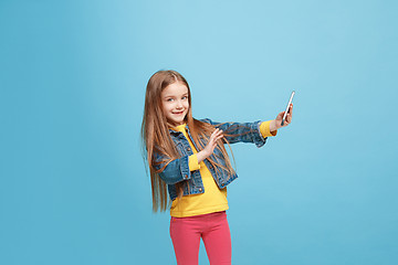 Image showing The happy teen girl standing and smiling against blue background.