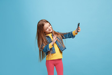 Image showing The happy teen girl standing and smiling against blue background.