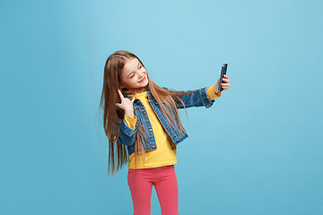 Image showing The happy teen girl standing and smiling against blue background.