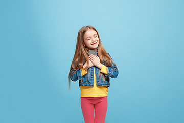 Image showing The happy teen girl standing and smiling against blue background.