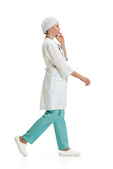 Image showing Beautiful young woman in white coat posing at studio. Full length studio shot isolated on white.