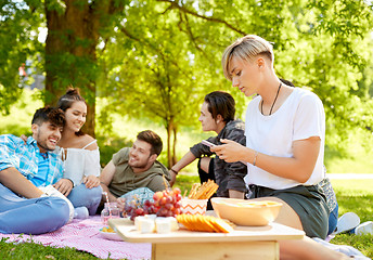 Image showing woman using smartphone at picnic with friends