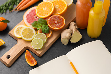 Image showing close up of fruits, juices and notebook on table