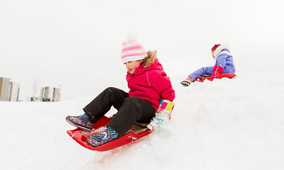 Image showing happy little girl sliding down on sled in winter