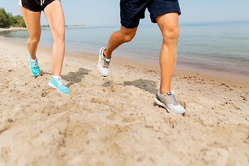 Image showing legs of sportsmen in sneakers running along beach