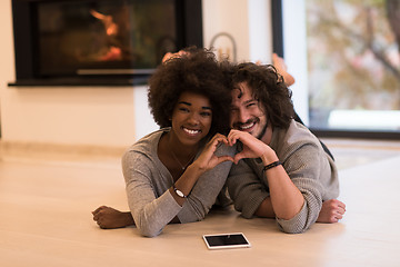 Image showing multiethnic couple showing a heart with their hands on the floor