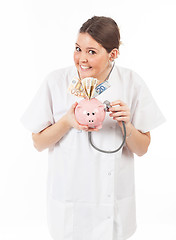 Image showing happy woman doctor with piggy bank full of money