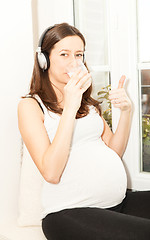 Image showing pregnant women drink a glass of milk and listening to music