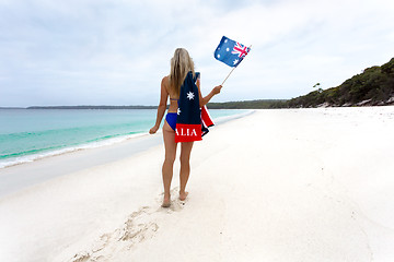 Image showing Woman walking along idyllic beach with Australian flag