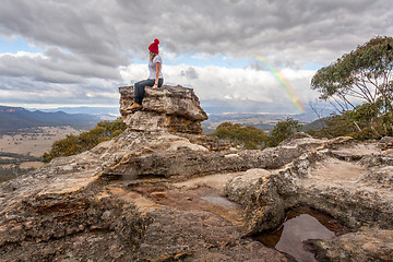 Image showing Woman perched on rock pillar peak with the best views below braving the mountain chill