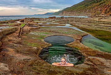 Image showing Female enjoying Figure 8 Pools on coastal rock shelf