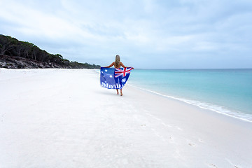 Image showing Aussie girl walking along pristine beach with Australian flag