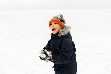 Image showing happy little boy playing with snow in winter