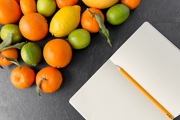 Image showing close up of fruits and notebook on slate table top