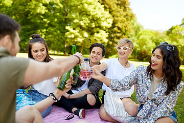 Image showing happy friends clinking drinks at summer park