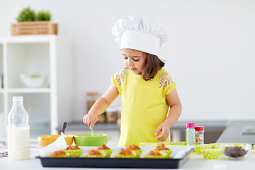 Image showing little girl in chefs toque baking muffins at home