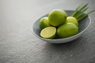 Image showing close up of limes in bowl on slate table top