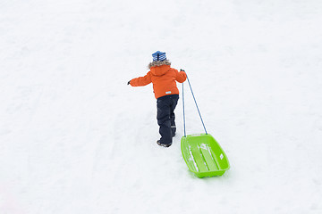 Image showing little boy with sled climbing snow hill in winter