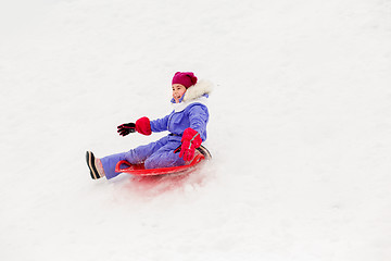 Image showing girl sliding down on snow saucer sled in winter