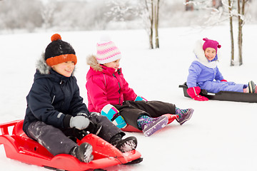 Image showing happy little kids sliding on sleds in winter