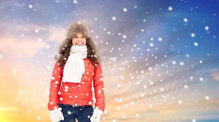 Image showing happy woman in winter fur hat over sky and snow