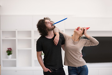 Image showing couple in party hats blowing in whistle