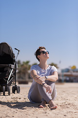 Image showing Young mother with sunglasses relaxing on beach