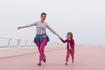 Image showing mother and cute little girl on the promenade by the sea