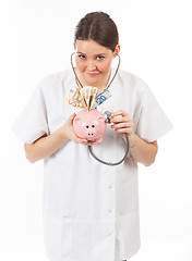 Image showing happy woman doctor with piggy bank full of money